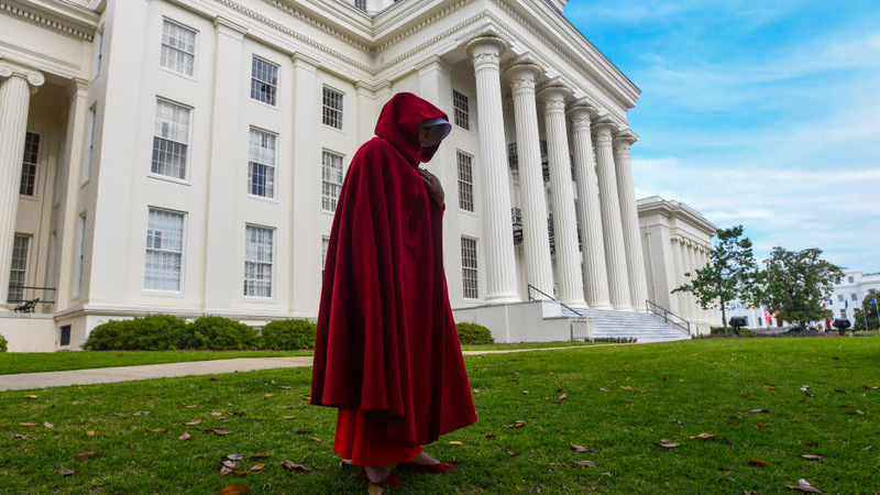 A protester dons a red cloak and white wings to protest Alabama’s recent near-total abortion ban.